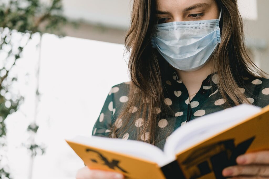 young smart lady reading book during coronavirus pandemic